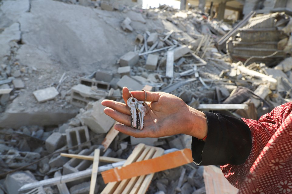 Gazze'deki El-Şati kampında yerinden edilmiş Filistinli bir kadın, yıkılan evinin anahtarlarını elinde tutuyor.